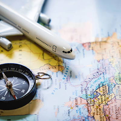 selective focus of miniature tourist on compass over map with plastic toy airplane,abstract background to travel concept.
